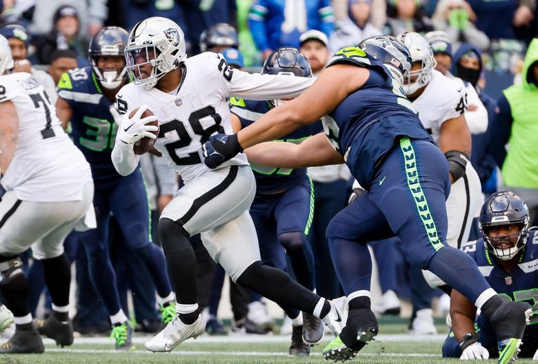 Las Vegas Raiders running back Josh Jacobs stiff arms Seattle Seahawks defensive tackle Al Woods on his way to a 30-yard touchdown run during the second quarter. (Jennifer Buchanan / The Seattle Times)