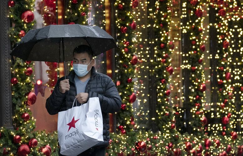 FILE – In this Nov. 30, 2020 file photo, a shopper walks by a holiday window display in New York. Financial educators are often working on overdrive during the holiday shopping season, dispensing advice to consumers about budgeting and staying out of debt. We asked five financial educators how they personally survive the holiday season with their finances intact. They shared some novel strategies, such as saving for the season starting in January and even buying gifts that early, giving nontraditional presents and focusing on next year’s financial goals instead of gifts. (AP Photo/Mark Lennihan, File) NYPS203 NYPS203