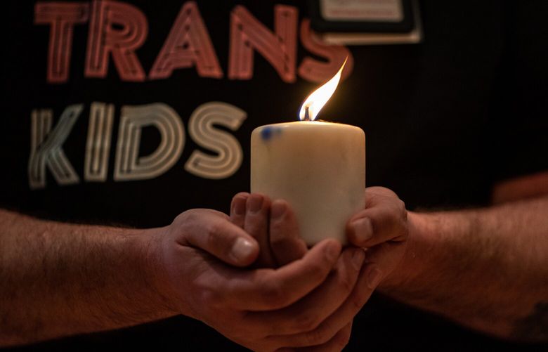 Executive Director of Diversity Alliance of the Puget Sound Oliver Webb holds a candle that has not been burned since the 2016 Pulse nightclub shooting during a vigil at the University Unitarian Church on Trans Day of Remembrance, Sunday, Nov. 20, 2022. TDOR Seattle Founder Astro Pittman, the owner of the candle, chose to burn it again during the vigil because of the Club Q shooting that happened the day prior in Colorado Springs.