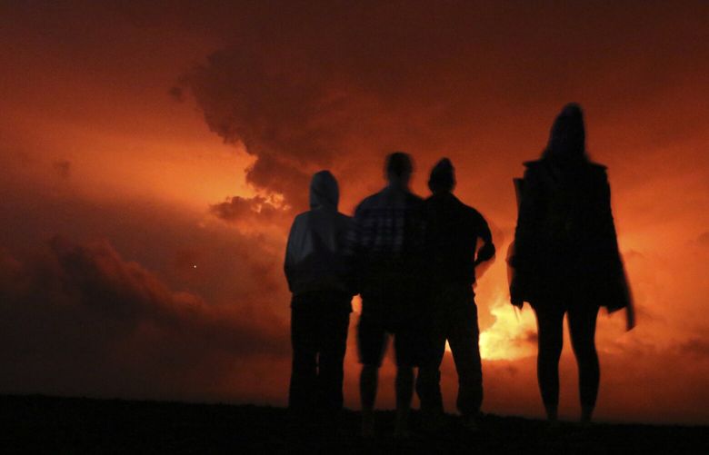 People watch the glow from lava erupting from Hawaii’s Mauna Loa volcano, Monday, Nov. 28, 2022 in Hilo, Hawaii. (AP Photo/Caleb Jones) HICJ102 HICJ102