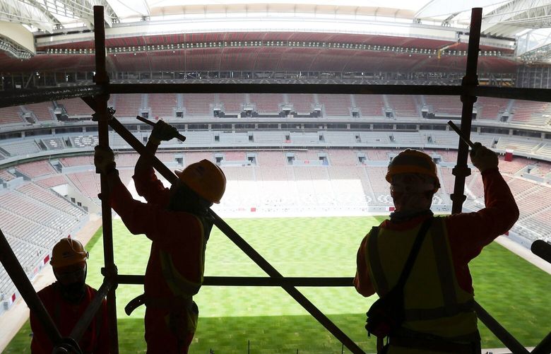 FILE – Laborers remove scaffolding at the Al Bayt stadium in Al Khor, Qatar, about 50 kilometers (30 miles) north of Doha, Monday, April 29, 2019. Migrant laborers who built Qatar’s World Cup stadiums often worked long hours under harsh conditions and were subjected to discrimination, wage theft and other abuses as their employers evaded accountability, a rights group said in a report released Thursday. (AP Photo/Kamran Jebreili, File) QAT503
