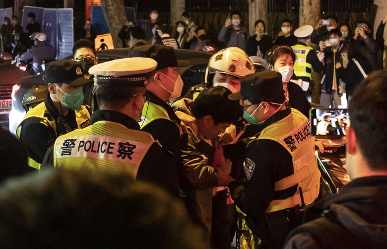 Police officers detain a man in Shanghai, China, on Sunday night, Nov. 27, 2022. In a country where protests are swiftly quashed, many who gathered to voice their discontent over COVID lock-down rules – under the watchful eye of the police – were uncertain about how far to go. (The New York Times) NYT1 NYT1