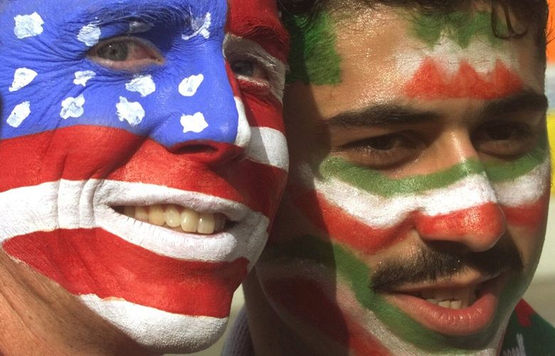 FILE – Mike Moscrop, left, from Orange County, Calif., poses with Amir Sieidoust, an Iranian supporter living in Holland outside the Gerlain Stadium in Lyon, June 21, 1998, before the start of the USA vs Iran World Cup soccer match. Iran defeated the U.S. 2-1 for its first World Cup win, eliminating them after just two games. A rematch between the U.S. and Iran will be played, Tuesday, Nov. 29, 2022. (AP Photo/Jerome Delay) NYPS206 NYPS206