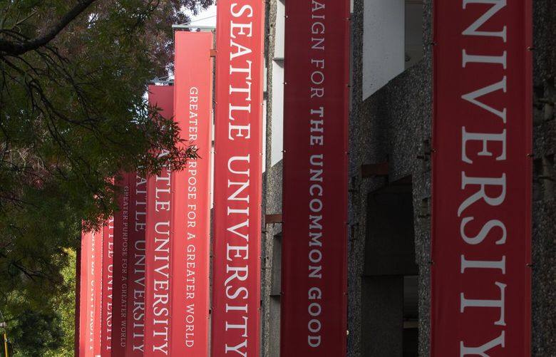 A woman walks past a parking garage at Seattle University along Broadway in Seattle Thursday, October 15, 2020. College enrollment, which is down only slightly at most Washington campuses this year, is actually up at the UW Seattle. Most kids also seem to be returning to campus, even though 90% of classes are online. 215376