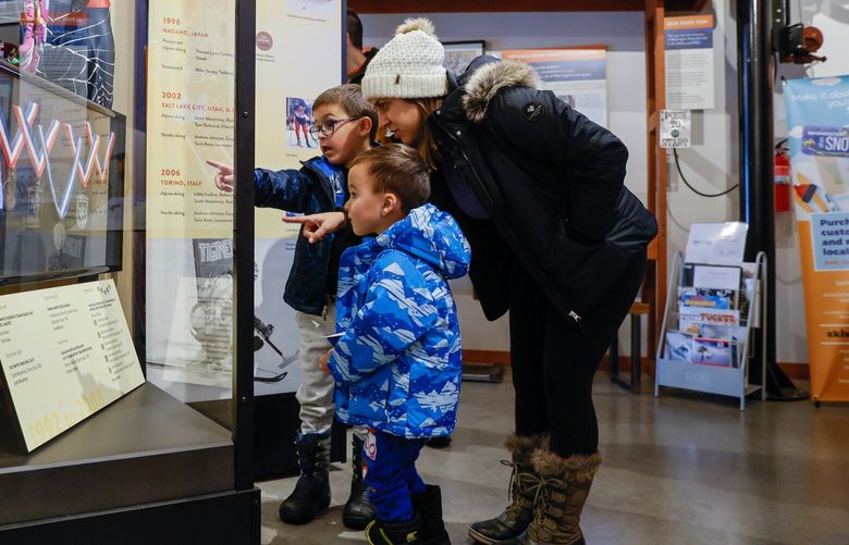 Six-year-old Caleb Deappolonio and mom Tiffany point out various skiing medals to three-year old brother Evan at the Washington State Ski & Snowboard Museum at Snoqualmie Pass Saturday, Nov. 26, 2022. The Deappolonios had been up tubing at the pass and stopped in for a bite to eat at The Commonwealth when they noticed the museum right next door and decided to pay it a visit. 222310