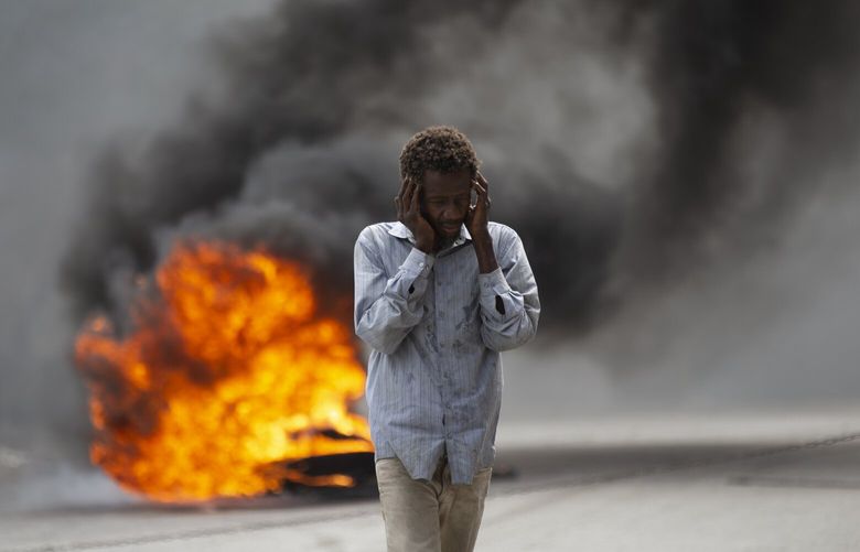 A man walks past a burning barricade during a protest over the death of journalist Romelson Vilsaint, in Port-au-Prince, Haiti, Sunday, Oct. 30, 2022. Vilsaint died Sunday after being shot in the head when police opened fire on reporters demanding the release of one of their colleagues who was detained while covering a protest, witnesses told The Associated Press.  (AP Photo/Odelyn Joseph) XRE114 XRE114