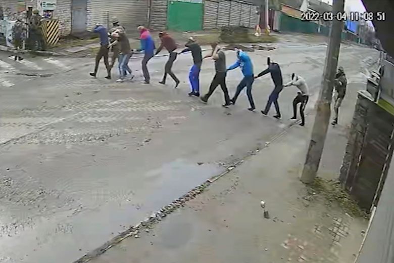 In this image from March 4, 2022, surveillance video provided by the Ukrainian government, Russian troops lead nine men at gunpoint to their headquarters on Yablunska Street in Bucha, where they would be tortured and executed. The men were picked up as part of what Russian soldiers called “zachistka” – cleansing. They hunted people on lists prepared by their intelligence services and went door to door to identify and neutralize potential threats. (Ukrainian government via AP)