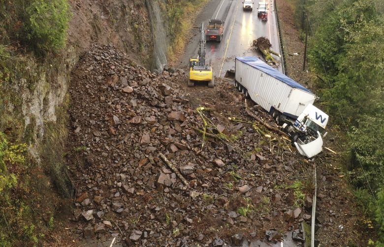 In this photo provided by the Oregon Department of Transportation, crews work to clear debris and remove a disabled truck on U.S. 30 east of Astoria, Ore., Wednesday, Nov. 30, 2022, after a landslide Tuesday night. (Oregon Department of Transportation via AP) FX401 FX401
