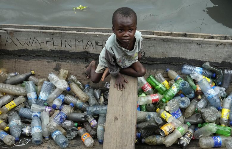 FILE – A child sits inside a canoe with empty plastic bottles he collected to sell for recycling in the floating slum of Makoko in Lagos, Nigeria, Nov. 8, 2022. More than 2,000 experts plan to wrap up early negotiations Friday, Dec. 2, on plastic pollution at one of the largest global gatherings ever to address the crisis. (AP Photo/Sunday Alamba, File) CLI608 CLI608