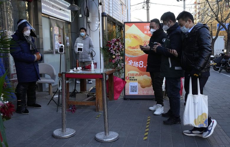 Residents show their health code before they enter a market with some shops re-opening for business as restrictions are eased in Beijing, Saturday, Dec. 3, 2022. Chinese authorities on Saturday announced a further easing of COVID-19 curbs with major cities such as Shenzhen and Beijing no longer requiring negative tests to take public transport. (AP Photo/Ng Han Guan) XHG117 XHG117