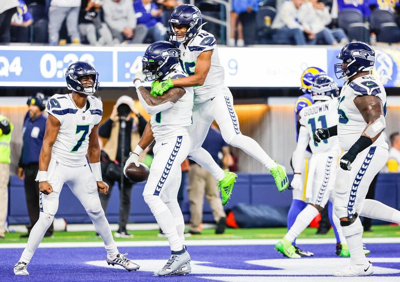 Geno Smith, left, and Tyler Lockett celebrate DK Metcalf making the key catch in the end zone in the fourth quarter. (Dean Rutz / The Seattle Times)