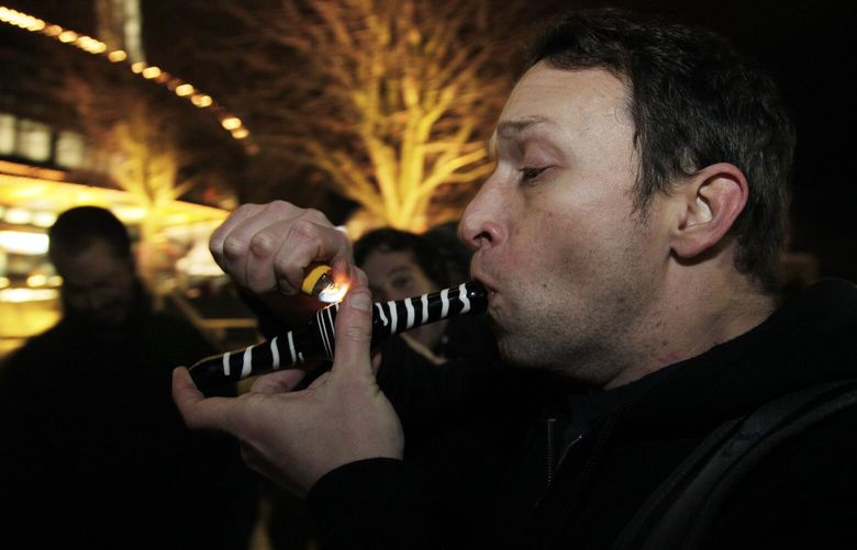 Gary Parrish smokes marijuana in a glass pipe, Thursday, Dec. 6, 2012, just after midnight at the Space Needle in Seattle. Possession of marijuana became legal in Washington state at midnight, and several hundred people gathered at the Space Needle to smoke and celebrate the occasion, even though the new law does prohibit public use of marijuana. (AP Photo/Ted S. Warren)