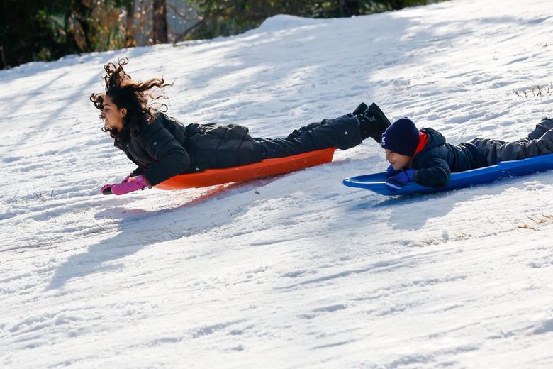 In this photo from Nov. 26, 11-year-old Laila Imam of Gig Harbor catches air as she and 5-year-old brother Zayn cruise down the Hyak Sno-Park sled hill near Snoqualmie Pass. Winter in Washington is a dream for snow lovers. (Jennifer Buchanan / The Seattle Times)