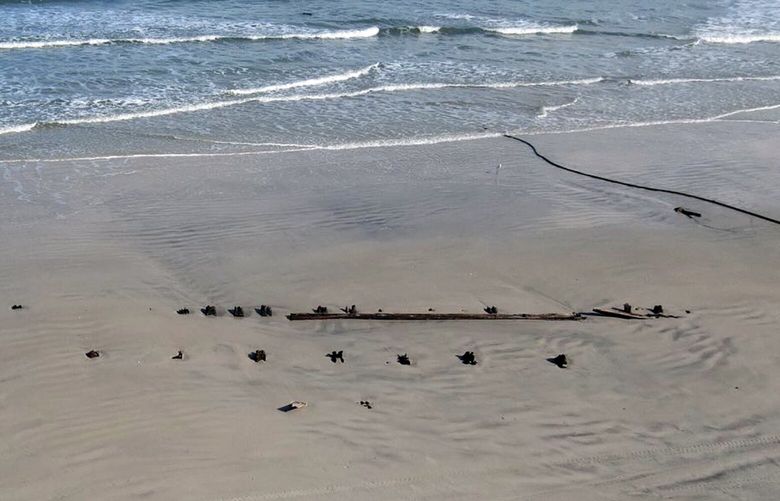A photo provided by Volusia County, Fla., shows a mystery object protruding through the sand at Daytona Beach Shores. Some theories are that it is a barrier, a shipwreck, a portion of an old pier, or spectator seating from when NASCAR had races on the beach. (Volusia County via The New York Times) – NO SALES; EDITORIAL USE ONLY-