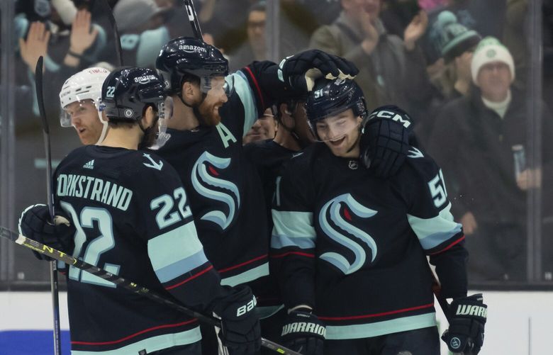 Seattle Kraken forward Shane Wright, right, is congratulated by teammates forward Oliver Bjorkstrand, left, and defenseman Adam Larsson after scoring a goal during the first period of an NHL hockey game, Tuesday, Dec. 6, 2022, in Seattle. (AP Photo/Stephen Brashear) WASB105 WASB105