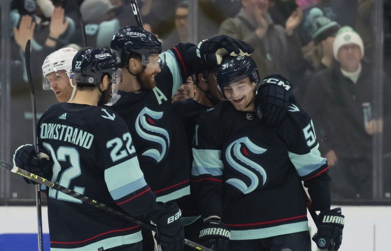 Seattle Kraken forward Shane Wright, right, is congratulated by teammates forward Oliver Bjorkstrand, left, and defenseman Adam Larsson after scoring a goal during the first period of an NHL hockey game, Tuesday, Dec. 6, 2022, in Seattle. (AP Photo/Stephen Brashear) WASB105 WASB105