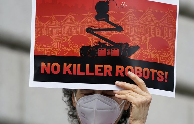 A woman holds up a sign while taking part in a demonstration about the use of robots by the San Francisco Police Department outside of City Hall in San Francisco, Monday, Dec. 5, 2022. The unabashedly liberal city of San Francisco became the unlikely proponent of weaponized police robots this week after supervisors approved limited use of the remote-controlled devices, addressing head-on an evolving technology that has become more widely available even if it is rarely deployed to confront suspects. (AP Photo/Jeff Chiu) CAJC105 CAJC105