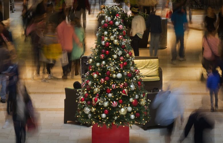 Black Friday shoppers scurry past a Christmas tree as they look for bargains at Bellevue Square Friday, November 25, 2016. The place was packed all day long.