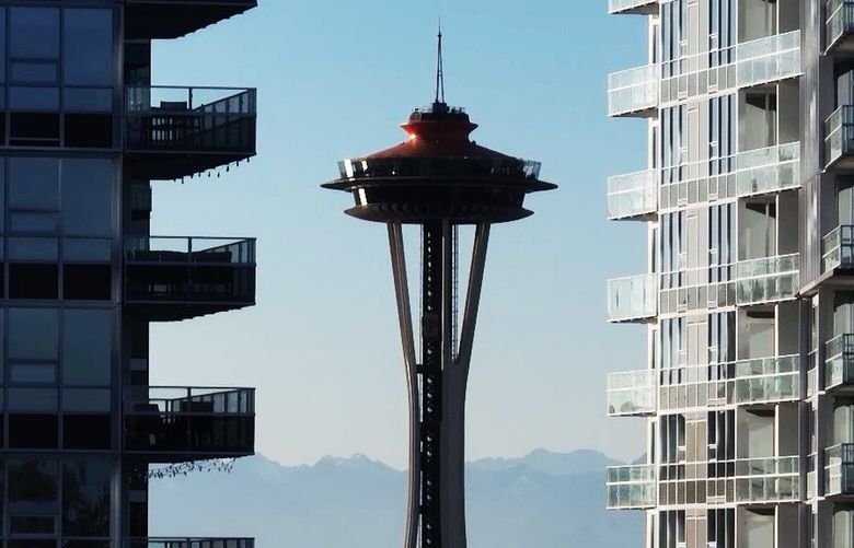The Space Needle peeks through two high rise buildings on a sunny day on Nov. 18, 2022.