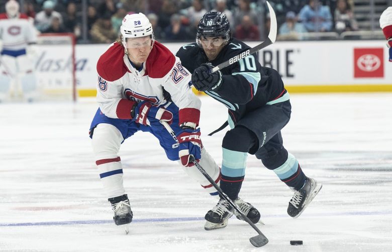 Montreal Canadiens forward Christian Dvorak, left, and Seattle Kraken forward Matty Beniers battle for the puck during the first period of an NHL hockey game, Tuesday, Dec. 6, 2022, in Seattle. (AP Photo/Stephen Brashear) WASB101 WASB101