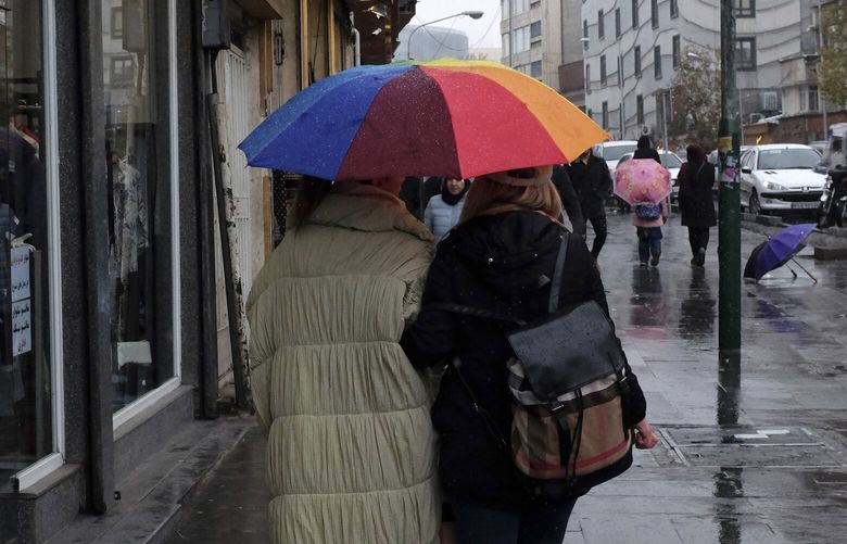 Two women walk in a rainy weather at Tajrish bazaar in northern Tehran, Iran, Monday, Dec. 5, 2022. Confusion over the status of Iran’s religious police grew as state media cast doubt on reports the force had been shut down. (AP Photo/Vahid Salemi) VAH103 VAH103