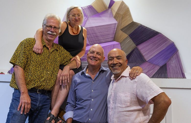 The 4 founders of Good Arts, from left, Steve Coulter, Jane Richlovsky, Greg Smith, and Ali Ghambari, Tuesday, Aug. 9, 2022 in downtown Seattle. In the background is the work “Aotearoa” by Savina Mason, one of the artists with a studio here.