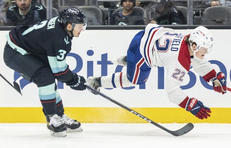 Seattle Kraken defenseman Will Borgen, left, and Montreal Canadiens forward Cole Caufield battle for the puck during the first period of an NHL hockey game, Tuesday, Dec. 6, 2022, in Seattle. (AP Photo/Stephen Brashear) WASB102 WASB102