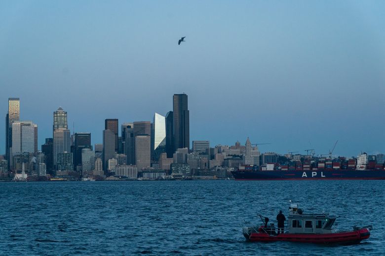 A man takes in the Seattle skyline from his boat as twilight falls on Saturday, Dec. 3, 2022. (Kylie Cooper / The Seattle Times)