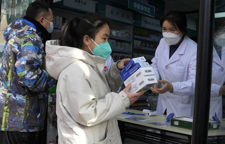 A resident carries away medicine bought at a pharmacy in Beijing, Friday, Dec. 9, 2022. China began implementing a more relaxed version of its strict “zero COVID” policy on Thursday amid steps to restore normal life, but also trepidation over a possible broader outbreak once controls are eased. (AP Photo/Ng Han Guan) XHG119 XHG119