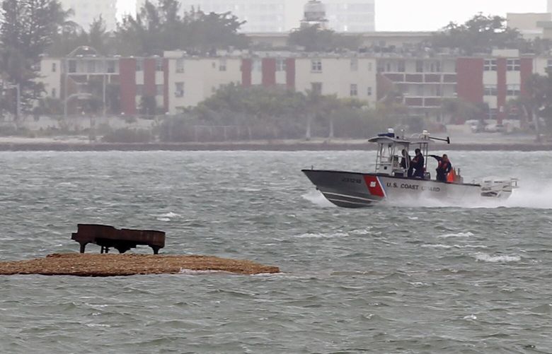 A U.S. Coast Guard boat passes near a grand piano on a sandbar in Biscayne Bay, Tuesday, Jan. 25, 2011 in Miami. The piano recently showed up on the sandbar, about 200 yards from condominiums on the shore. While officials aren’t sure how it got there, they know it won’t be going anywhere unless it becomes a hazard to wildlife or boaters. (AP Photo/Wilfredo Lee) FLWL101