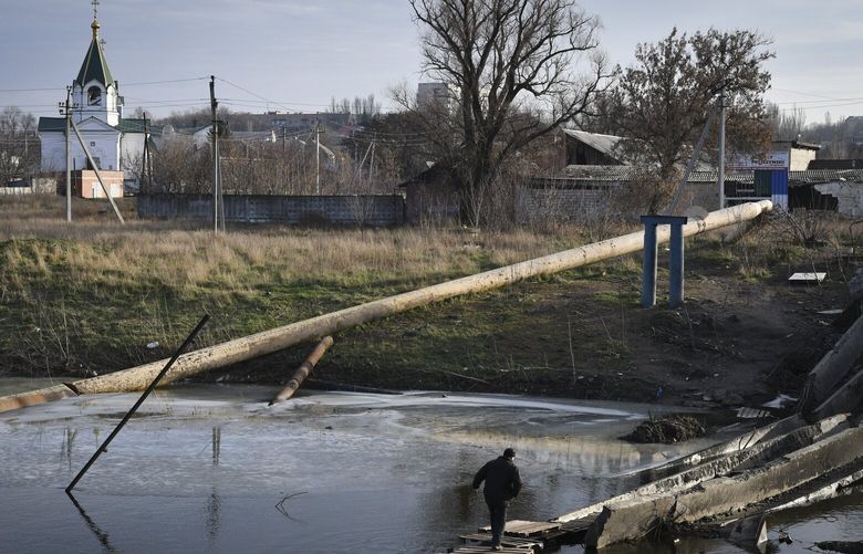 A man crosses the river on the debris of a damaged bridge in Bakhmut, the site of the heaviest battles with the Russian troops, in the Donetsk region, Ukraine, Sunday, Dec. 11, 2022. (AP Photo/Andriy Andriyenko) XEL103 XEL103