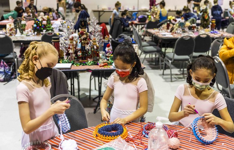 From left, Grace Magdsick, Ellie Wang and Laura Hu bring loom and yarn to make hats for donation at the kids dressing room backstage before a performance of PNWs “Nutcracker” at McCaw Hall in Seattle on Thursday, Dec. 8, 2022.