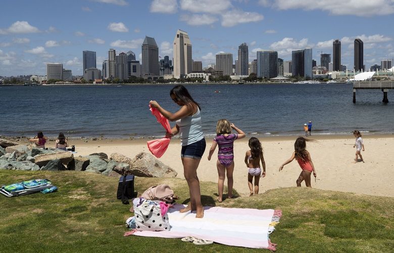 FILE – In this May 19, 2020, file photo, a family sets up at a beach looking out toward the San Diego skyline in Coronado, Calif. Stephen Leatherman, a coastal scientist and professor at Florida International University, has been drafting a list of the best beaches in the U.S., under alias “Dr. Beach” since 1991. For 2021, he has named Coronado Beach the eighth-best beach in the country. (AP Photo/Gregory Bull, File)