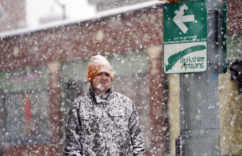 A man is covered in snow on Fenn Street in Pittsfield, Mass, Friday, Dec. 16, 2022. (Ben Garver/The Berkshire Eagle via AP) MAPIT101 MAPIT101