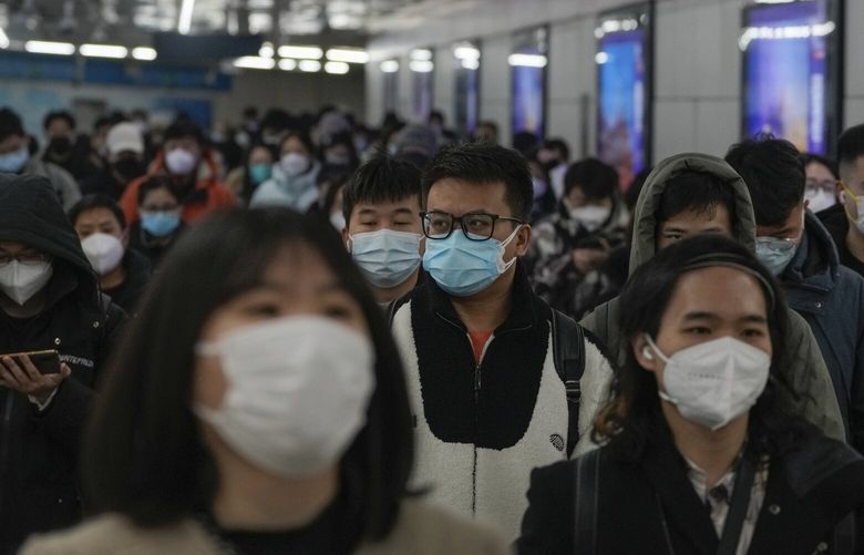 Masked commuters walk through a walkway in between two subway stations as they head to work during the morning rush hour in Beijing, Tuesday, Dec. 20, 2022. China continues to adapt to an easing of strict virus containment regulations. (AP Photo/Andy Wong) XAW101 XAW101