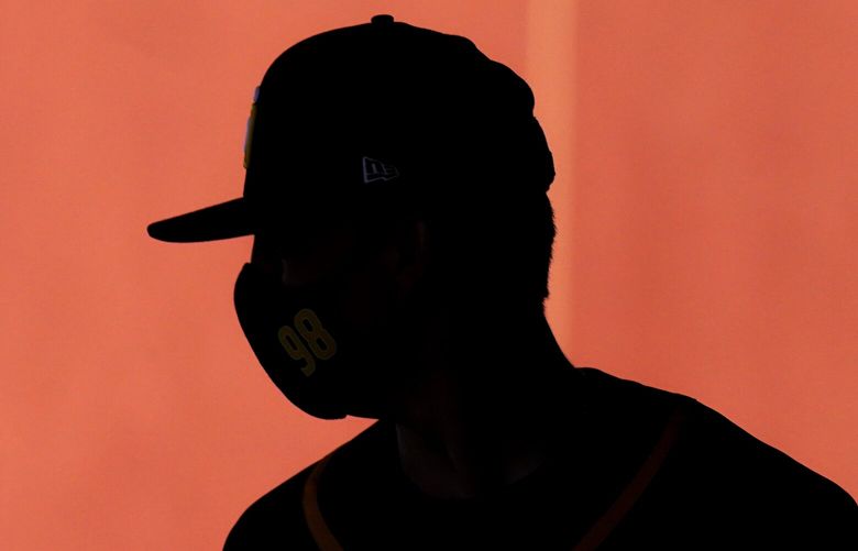 FILE – In this Saturday, Feb. 27, 2021 file photo, a player wears a face mask as he walks to a drill during San Diego Padres spring training baseball practice in Peoria, Ariz. A study published on Thursday, March 4, 2021 in JAMA Cardiology, suggests that heart inflammation is uncommon in pro athletes whoâ€™ve had mild COVID-19 and most donâ€™t need to be sidelined. (AP Photo/Charlie Riedel)