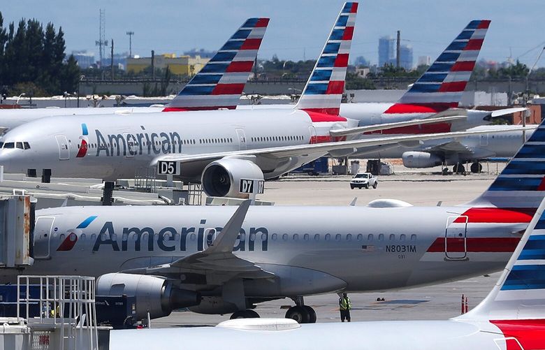 FILE – In this April 24, 2019, photo, American Airlines aircraft are shown parked at their gates at Miami International Airport in Miami. (AP Photo/Wilfredo Lee, File)