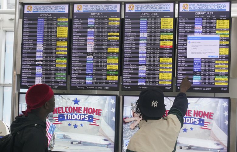 Passengers check the departure status of their flight at Fort Lauderdale- Hollywood International Airport, Thursday, Dec. 22, 2022, in Fort Lauderdale, Fla. More than 2,156 flights within, into or out of the U.S. had been canceled as of Thursday afternoon, according to the tracking site FlightAware. Airlines have also canceled 1,576 Friday flights.(AP Photo/Marta Lavandier) FLML104 FLML104