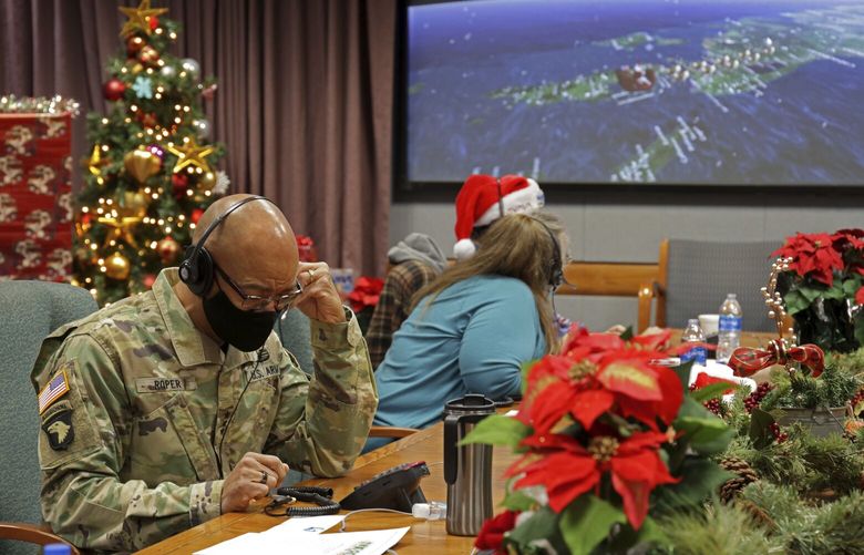 In this photo released by the U.S. Department of Defense, volunteers answer phones and emails from children around the globe during annual NORAD Tracks Santa event at Peterson Air Force Base in Colorado Springs, Colo., on Dec. 24, 2021. The U.S. military agency known for tracking Santa Claus as he delivers presents on Christmas Eve doesn’t expect COVID-19 or the “bomb cyclone” hitting North America to impact Saint Nick’s global travels this year. NORAD, the North American Aerospace Defense Command, is responsible for monitoring and defending the skies above North America. (Jhomil Bansil/U.S. Department of Defense via AP) FX503 FX503