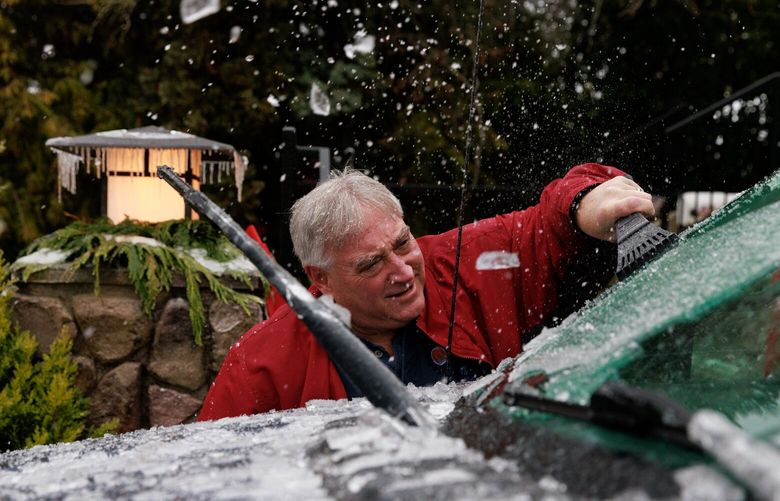 Lee Forte scrapes a thick layer of ice off his truck in West Seattle Friday morning Dec. 23, 2022. 
 222546