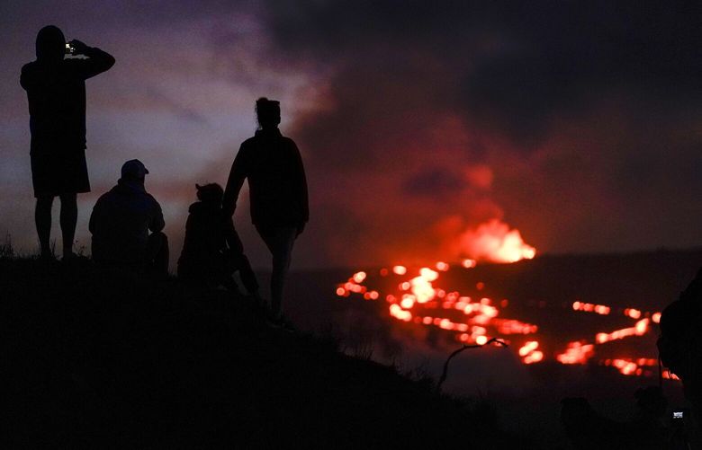 FILE – People watch lava from the Mauna Loa volcano Thursday, Dec. 1, 2022, near Hilo, Hawaii. U.S. scientists declared Tuesday, Dec. 13, 2022, that two active Hawaii volcanoes — one where lava destroyed hundreds of homes in 2018 and another where lava recently stalled before reaching a crucial Big Island highway — have stopped erupting. (AP Photo/Gregory Bull, File) FX203 FX203