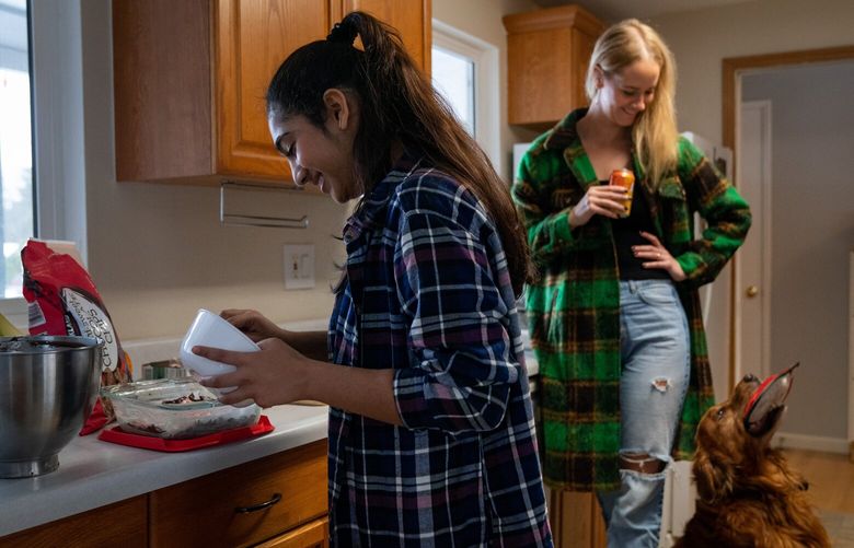 Tara Kankesh sprinkles crushed candy canes atop peppermint brownie batter as her mentor, Lindsey Greenlee, smiles down at her golden retriever, Bosun, on Sunday, Dec. 4, 2022. Kankesh and Greenlee have been matched through Big Sister, Little Sister since December 2019.