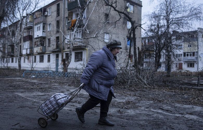 A local woman walks to the distribution point of humanitarian aid in front of housing which was damaged by Russian shelling in Kupiansk, Kharkiv region, Ukraine, Wednesday, Dec. 28, 2022. (AP Photo/Evgeniy Maloletka) MAL103 MAL103