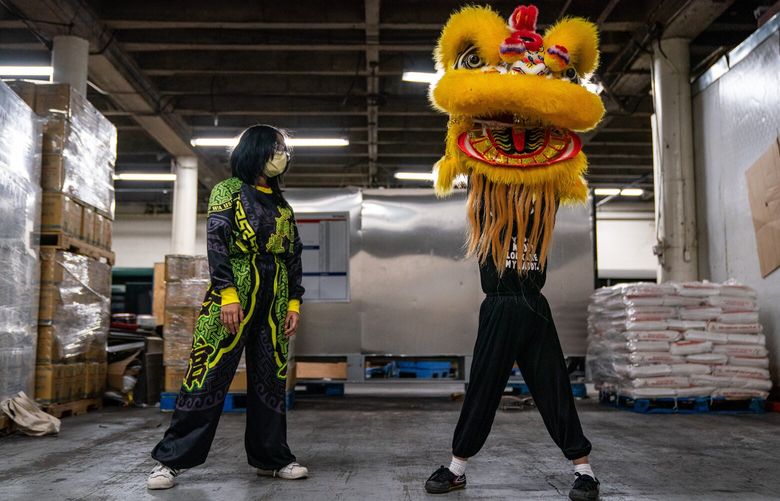 Tina Le, left, and Cooper Nguyen took turns moving with a lion head on at a warehouse the Mak Fai Dragon and Lion Dancing Association is currently using to practice in Little Saigon on Saturday, Dec. 17, 2022.
