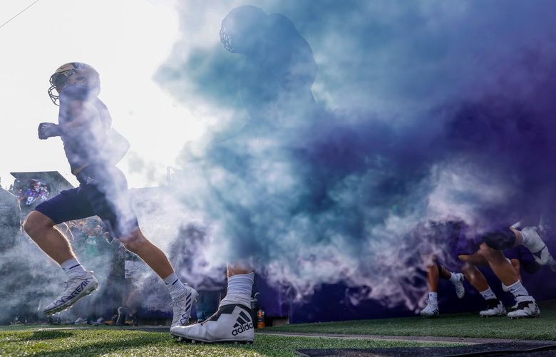 Washington Huskies players run through the smoke as they enter the field before the start of a game against Michigan State, Saturday, Sept. 17, 2022, in Seattle. 221586