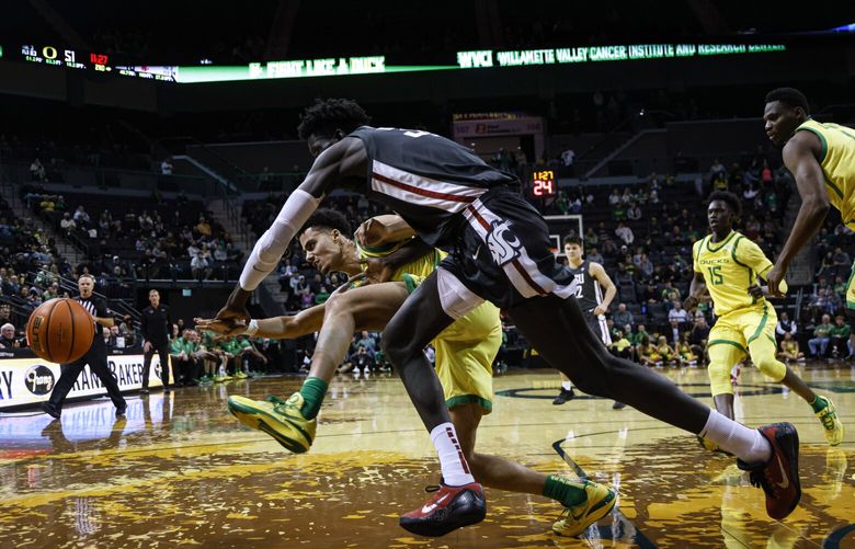 Oregon guard Will Richardson scrambles for the ball against Washington State forward Mouhamed Gueye, front, during the second half of an NCAA college basketball game in Eugene, Ore., Thursday, Dec. 1, 2022. (AP Photo/Thomas Boyd) ORTB110 ORTB110