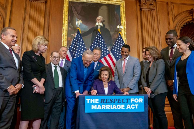 House Speaker Nancy Pelosi of Calif., accompanied by Senate Majority Leader Sen. Chuck Schumer of N.Y., center left, and other members of Congress, signs the H.R. 8404, the Respect For Marriage Act, on Capitol Hill in Washington, Thursday, Dec. 8, 2022.