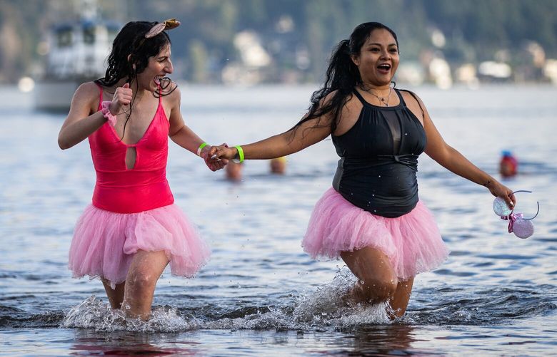 Melissa Valasky, left, and Sarai Flores walk back to the shore of Matthews Beach with wide smiles after conquering their first polar bear plunge on Sunday, Jan. 1, 2023.