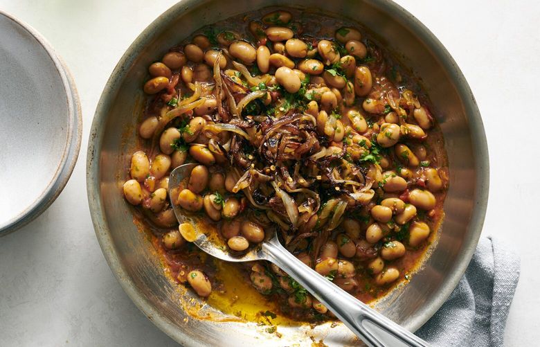 White beans with herbs and onions, Dec. 19, 2022. Canned cannellini beans quickly braised with olive oil, rosemary, tomato and golden fried onions make the best of your pantry. Food styled by Simon Andrews. (David Malosh/The New York Times) XNYT86 XNYT86