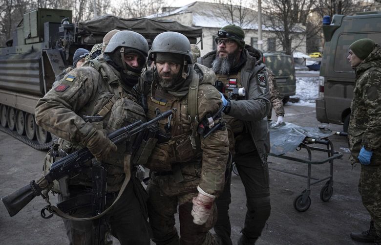 A Ukrainian serviceman carries his injured comrade evacuated from the battlefield into a hospital in Donetsk region, Ukraine, Monday, Jan. 9, 2023. (AP Photo/Evgeniy Maloletka) MAL102 MAL102